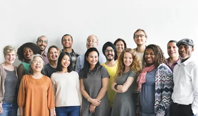 A diverse group of smiling business people standing together against a white wall
